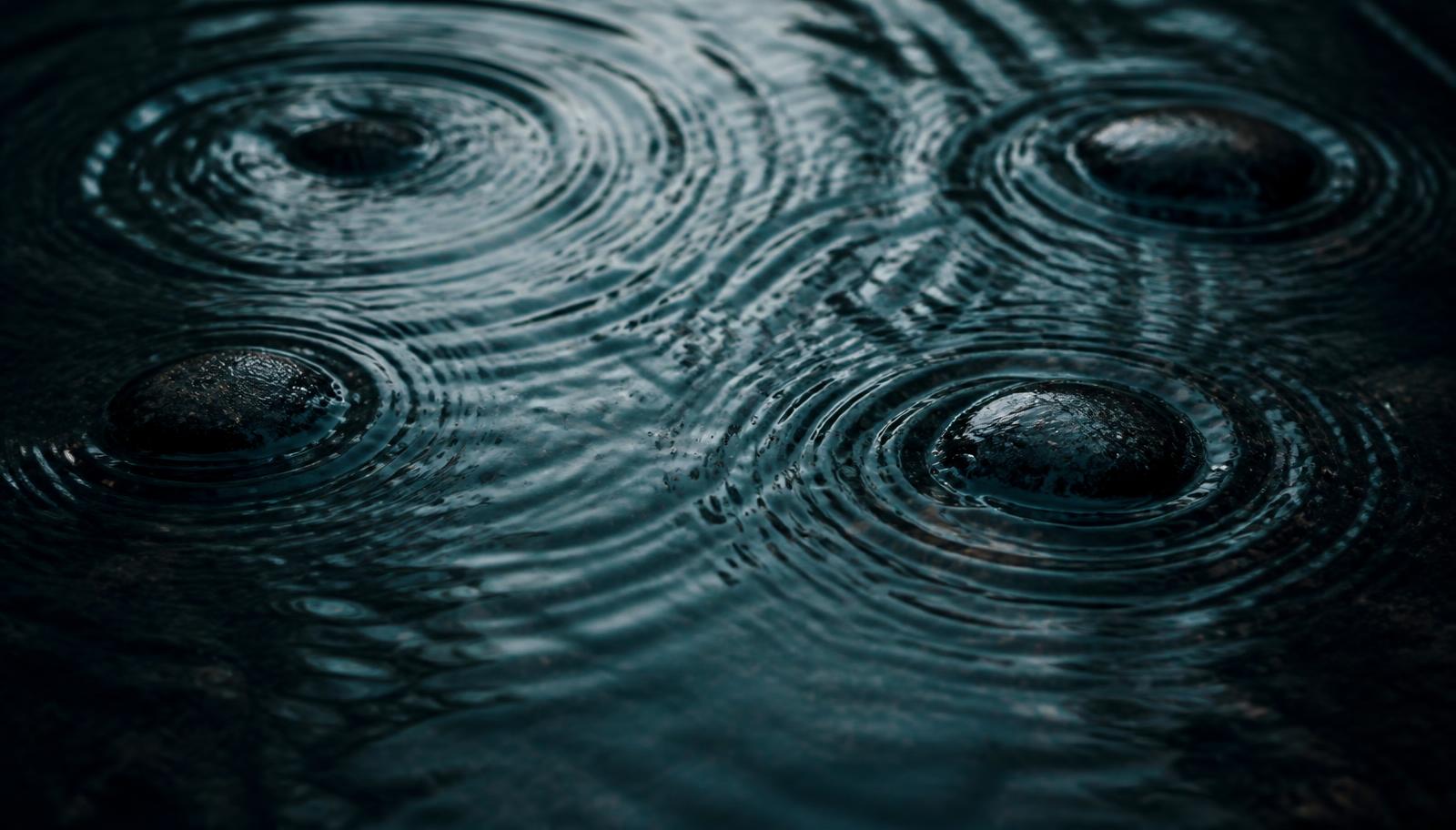 Dark ocean water disturbed by scattered stones creating overlapping ripples
