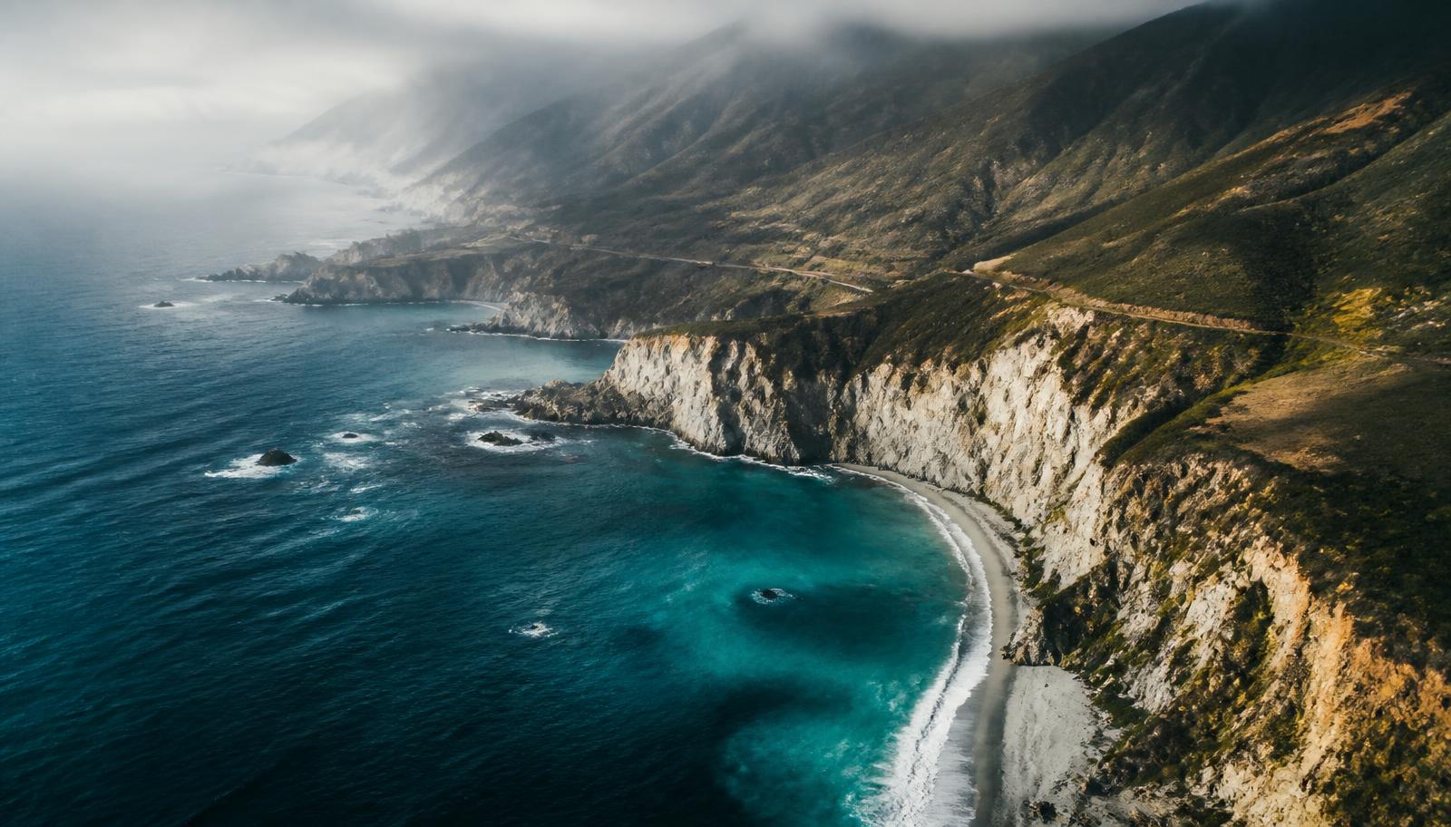 Aerial view of a dramatic coastline where deep teal ocean meets pale cliffs