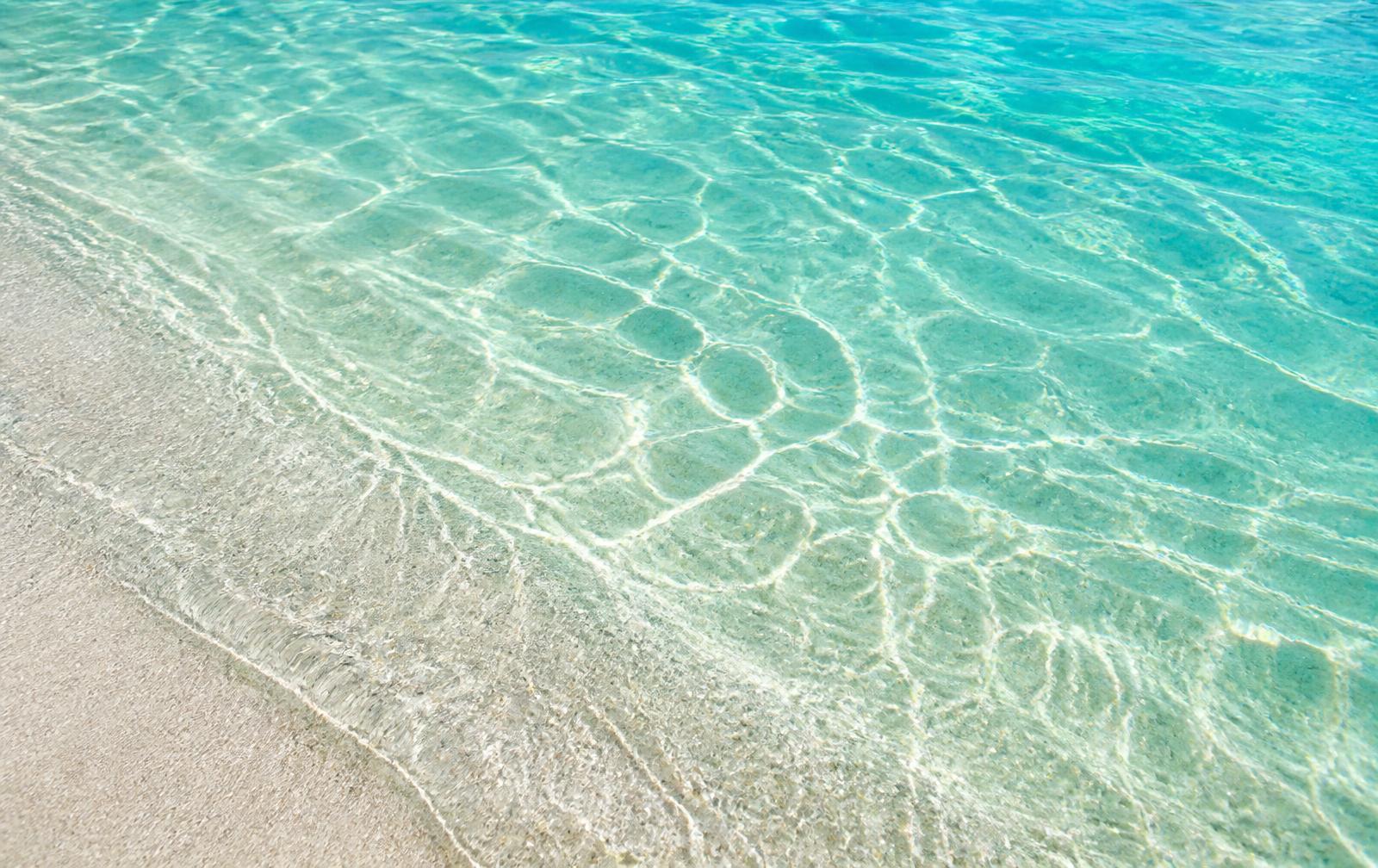 Clear shallow ocean water rippling over pale sand